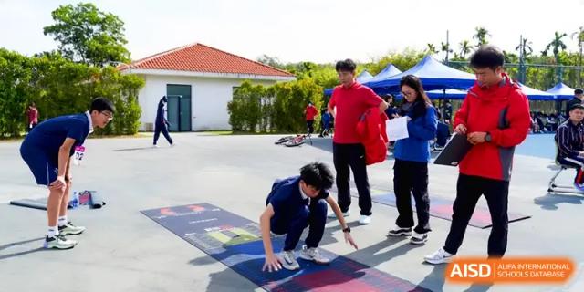 A student in a blue tracksuit prepares to start a race on an outdoor athletic track at Beijing Haidian Foreign Language Shi Yan School Hainan Campus.