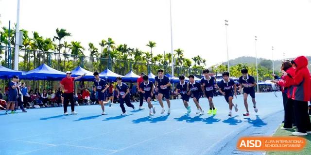 A group of students sprints down a blue running track during a competitive sports meet at Beijing Haidian Foreign Language Shi Yan School Hainan Campus.