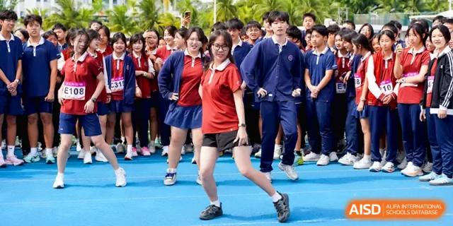 A student in a red shirt performs a dance or athletic movement on the blue field at Beijing Haidian Foreign Language Shi Yan School Hainan Campus.