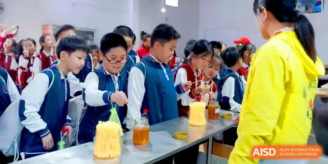 Students observe and participate in a science or health activity involving glass jars at Beijing Haidian Foreign Language Shi Yan School Hainan Campus.