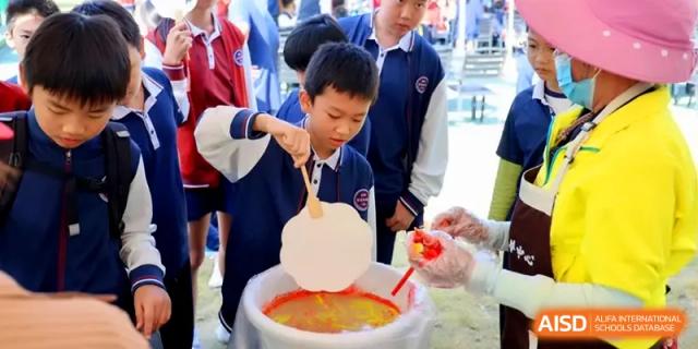 A student uses a large spoon to participate in a creative food or science demonstration at Beijing Haidian Foreign Language Shi Yan School Hainan Campus.