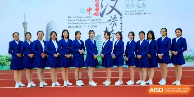 A group of female students in matching blue blazers and skirts pose together on an outdoor athletic track at Zhengzhou No.11 High School.