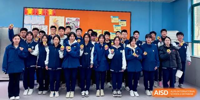 A large group of students in blue and white tracksuits pose together for a group photo indoors at Zhengzhou No.11 High School.
