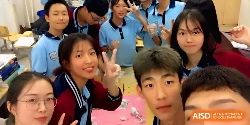 A group of students take a cheerful selfie together, with one girl making a peace sign in class at Zhengzhou No.11 High School.