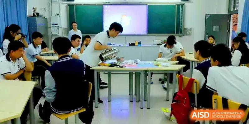 A student pours liquid into a beaker during a practical chemistry or biology experiment in a bright lab at Zhengzhou No.11 High School.