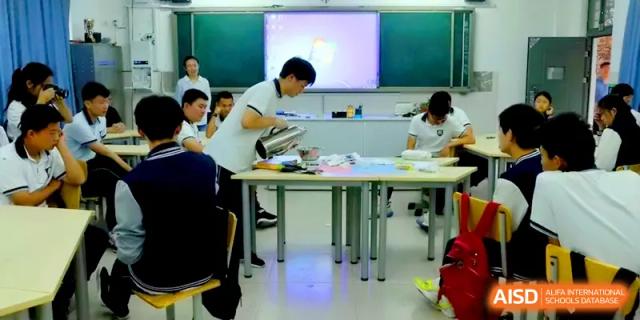 A student pours liquid into a beaker during a practical chemistry or biology experiment in a bright lab at Zhengzhou No.11 High School.