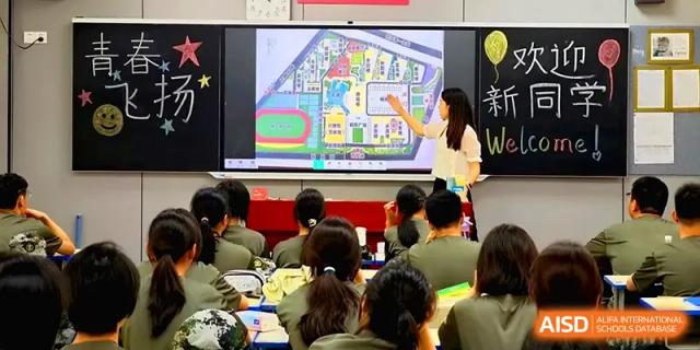 A teacher uses a digital screen to show a colorful map or floor plan to a class of attentive students at Zhengzhou No.11 High School.