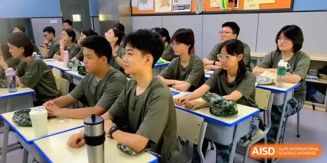 Students in green shirts sit at their desks, looking forward and listening to a lecture or presentation at Zhengzhou No.11 High School.