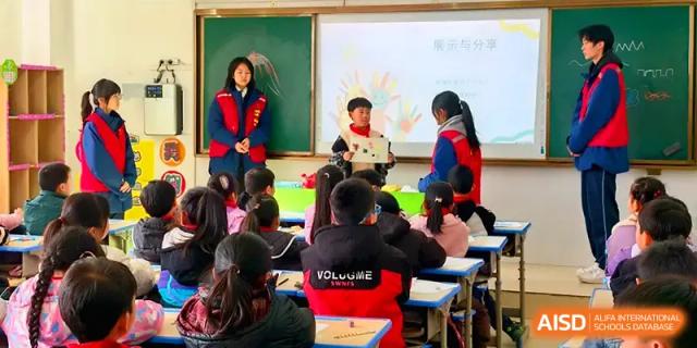 A young student presents a project to the rest of the class while a teacher watches from the side at Zhengzhou No.11 High School.