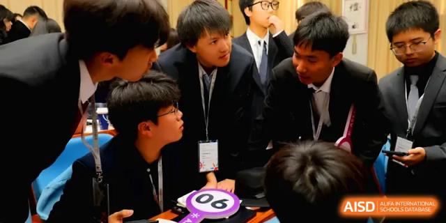 A group of students in suits huddle together to discuss a project or competition strategy at Zhengzhou No.11 High School.