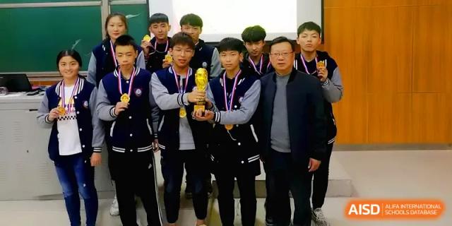 A group of young athletes in tracksuits proudly display a gold trophy after a sports victory at Zhengzhou No.11 High School.