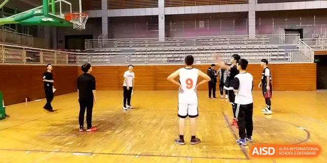 A basketball player wearing a number 9 jersey stands on the court during a game in the school gym at Zhengzhou No.11 High School.
