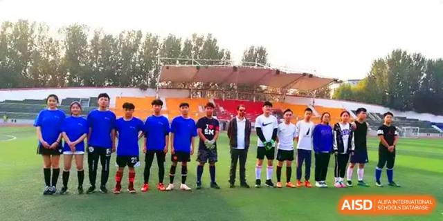 A soccer team in blue and white uniforms lines up on the field for a group photo before a game at Zhengzhou No.11 High School.