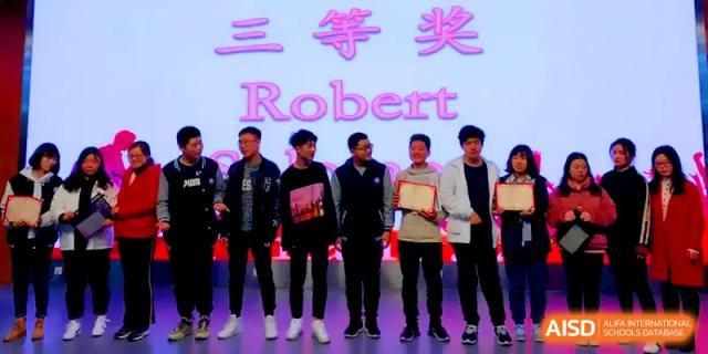 Students stand on a stage under purple lighting to receive awards for an academic or talent achievement at Zhengzhou No.11 High School.