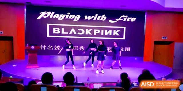 Students perform a synchronized dance routine on a stage with a "BLACKPINK" backdrop during a talent show at Zhengzhou No.11 High School.